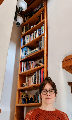 Rachel, founder of Shelfwright, standing in front of tall bookshelves